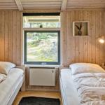 Zwei Betten, Holzwände, Fenster mit Blick nach draußen und kleine Wandregale.