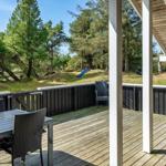 Terrasse mit Tisch und Stühlen, Blick auf Wald und Rutsche.