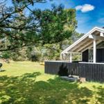 Moderne Hütte mit Terrasse, Grill und Picknicktisch im Gras.