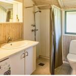 Badezimmer mit Dusche, Toilette und Waschbecken unter Holzwand