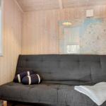 Graße Schlafcouch mit Kissen und Decke an Holzwand unter Karte.