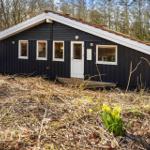 Schwarze Holzhütte mit weißer Tür und Fenstern im Wald. Gelbe Blumen im Vordergrund.