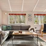 Wohnzimmer mit Sofa, Couchtisch und Sessel. Fenster mit Blick in den Wald.