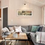 Ein Wohnzimmer mit grauem Sofa, Holztisch und Holzwänden.