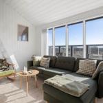 Wohnzimmer mit Sofa, Sessel und großem Fenster. Helle Wände und Holzboden.
