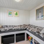 Zimmer mit L-förmigem Bett und Wandbildern an weißen Wänden.