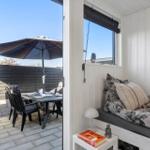 Ein Schlafzimmer mit Blick auf eine Terrasse mit Tisch, Stühlen und Sonnenschirm.