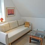 Wohnzimmer mit Sofa, Glas-Tisch und Fenster. Wandbild zeigt Leuchtturm.