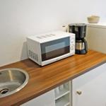 Küchenzeile mit Spüle, Mikrowelle, Kaffeemaschine und Kühlschrank.