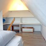 Schlafzimmer mit Dachschräge, Bett und Regalsystem.