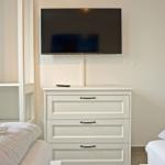Zimmer mit zwei Betten, Schrank und Wandfernseher.