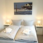 Zimmer mit Doppelbett, zwei Nachttischen und Wandbild an der Wand.