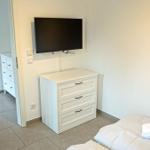 Schlafzimmer mit Bett, Schrank und Wand-TV. Blick in das Bad.