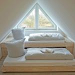 Zwei Matratzen auf Holzrahmen unter Dachschrägen mit Fenster