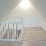 Dachgeschoss mit Holzboden und weißer Brüstung unter schrägen Wänden