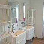 Badezimmer mit zwei Waschbecken, Spiegeln und Fenster mit pinken Jalousien.
