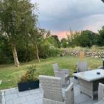 Terrasse mit Sitzgruppe, Garten und Blick auf Wald.