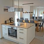 Küche mit Essbereich und Sitzgelegenheiten im Hintergrund.