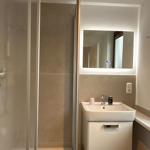 Bathroom with shower, sink, and lit mirror.
