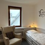 Bedroom with bed, armchair, and wall decoration.