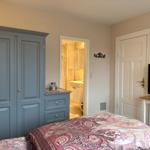 Schlafzimmer mit Bett, Kleiderschrank und TV. Badezimmer ist angrenzend.