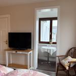 Schlafzimmer mit TV, Stuhl und Blick auf Balkon.