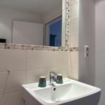 Waschbecken mit Spiegel und Mosaikfliesen an der Wand.