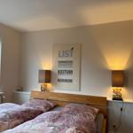 Schlafzimmer mit Bett, Wandbild und zwei Nachttischen mit Lampen.