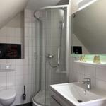 Bathroom with shower, sink, and toilet. Wall with Chanel poster.