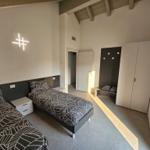 Zimmer mit zwei Betten, Kleiderschrank und Deckenbeleuchtung.