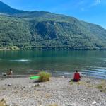 Seeufer mit Steinsandstrand, Menschen baden und entspannen.