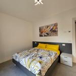 Schlafzimmer mit Bett, Nachttisch und Wandbild.