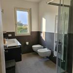 Badezimmer mit Dusche, Waschbecken und Toilette. Fenster mit Blick auf Garten.