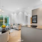 Modern eingerichteter Wohn- und Essbereich mit Kücheninsel und großem Fenster.