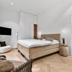 Schlafzimmer mit Bett, Kleiderschrank und TV. Badezimmer im Anschluss.