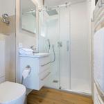 Bad mit Dusche, Waschbecken und Toilette. Holzfußboden und Heizung.