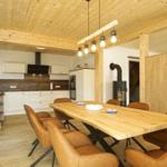 Essbereich mit Holztisch und Ledersitzen. Küche und Kamin im Hintergrund.
