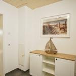 Eingangsbereich mit Schrank, Wandbild und Segelbootmodell.