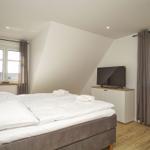 Schlafzimmer mit Doppelbett, Fernseher und Fenstern mit Vorhängen.