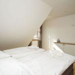 Schlafzimmer mit Doppelbett, Schrank und Fenster unter Dachschrägen.