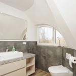 Badezimmer mit Waschtisch, Spiegel und Toilette unter Dachschrägen.
