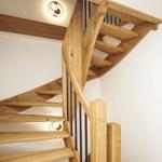 Holzgetreppe mit schwarzem Geländer und Deckenleuchte.