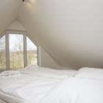 Schlafzimmer mit Doppelbett und großem Fenster zum Blick auf die Landschaft.