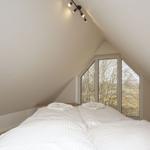 Schlafzimmer mit Doppelbett und großem Fenster zur Waldsicht.