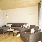Wohnzimmer mit grauem Sofa, zwei runden Tischen und Holzboden.