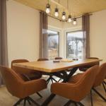 Esszimmer mit Holztisch, braunen Stühlen und großen Fenstern.