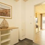 Eingangsbereich mit Schrank, Wandbild und Blick in Wohnbereich.