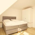 Schlafzimmer mit Doppelbett, Kleiderschrank und Holzboden.