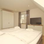 Schlafzimmer mit Doppelbett, Kleiderschrank und Fernseher