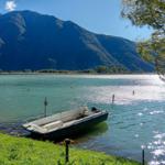 Ein kleines Boot liegt am Ufer eines Sees mit Bergen im Hintergrund.